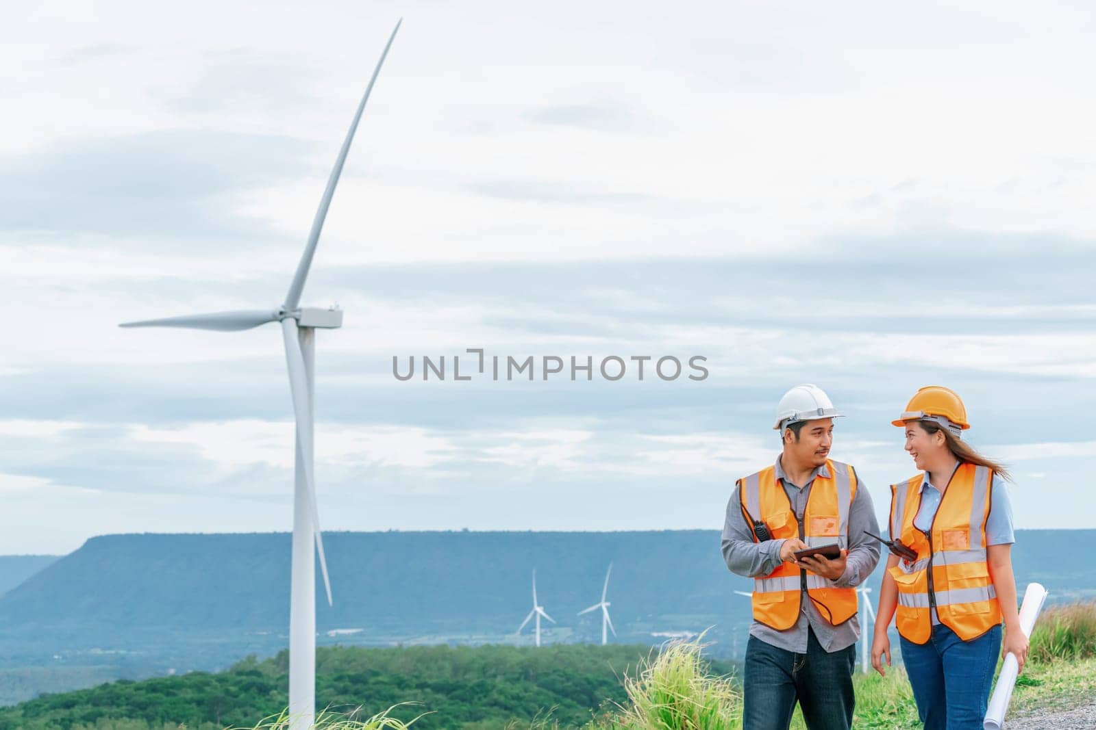 Progressive concept of engineers working in the wind farm atop of the mountain. by biancoblue
