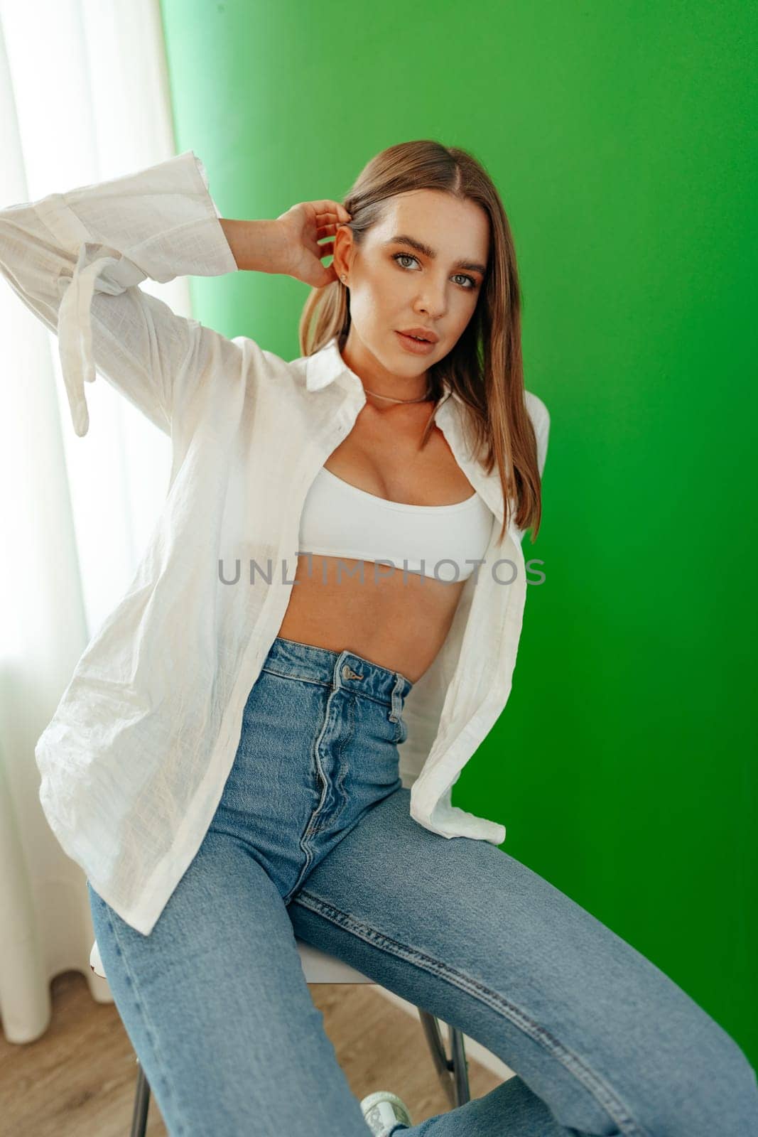 Portrait of attractive lovely girl wearing crop top and shirt posing over green studio background close up