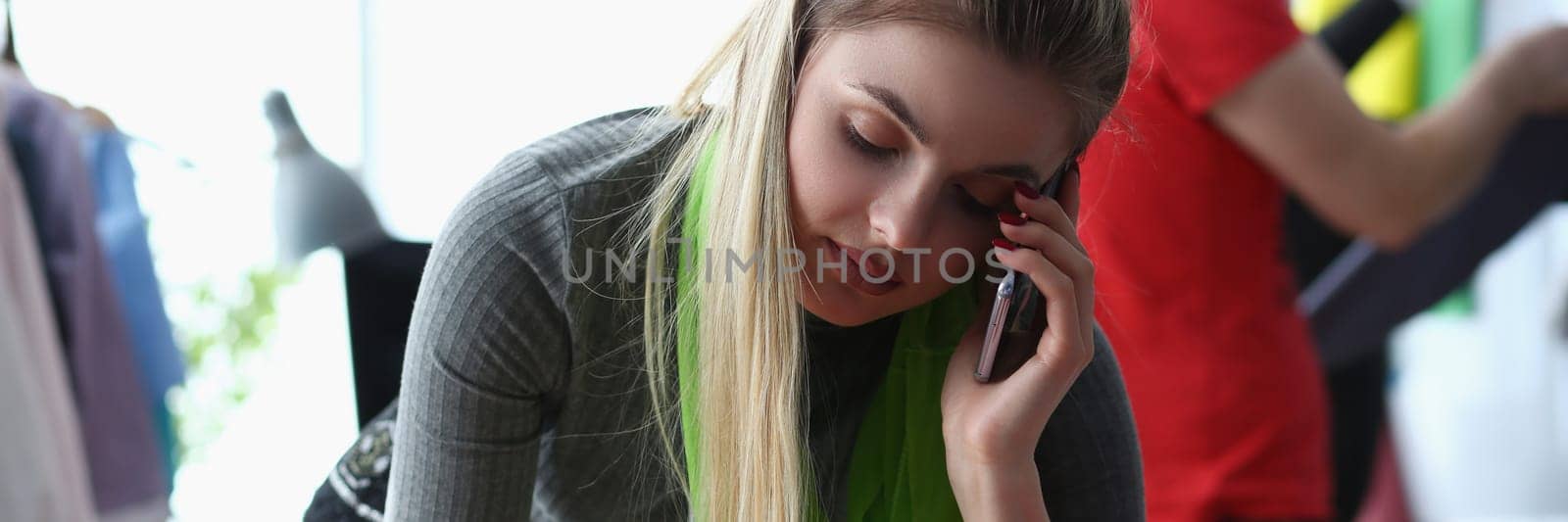 Working seamstress woman holds phone and takes orders from customers. Online ordering tailoring from seamstress designer concept