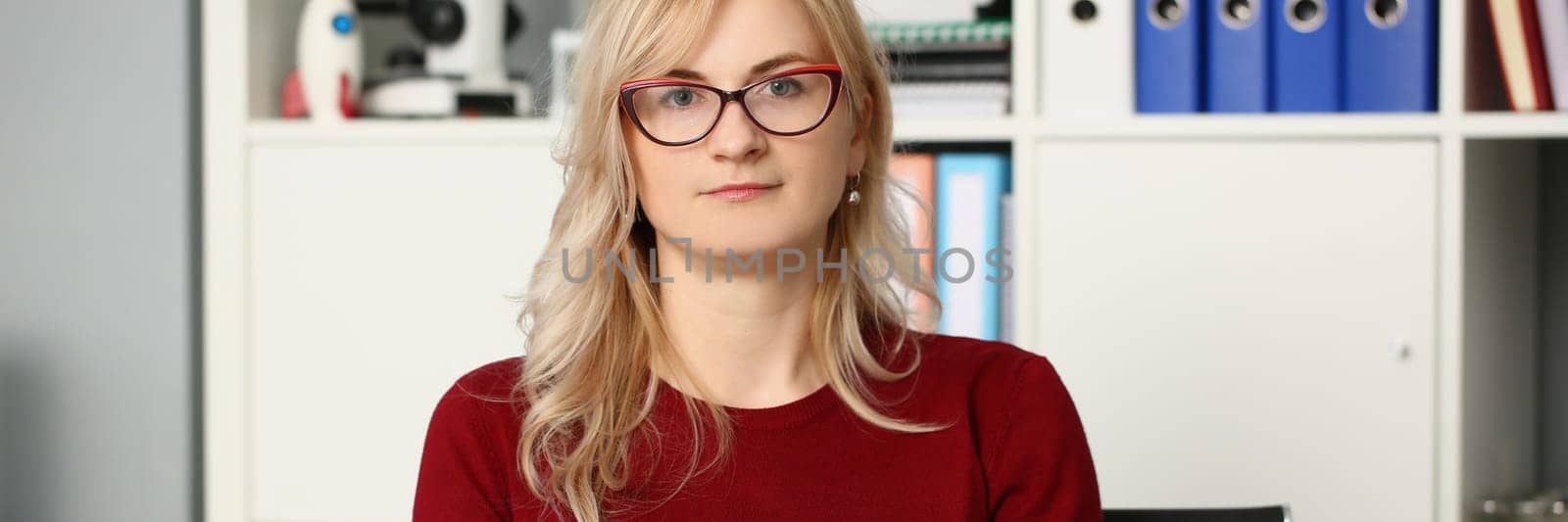 Portrait of businesswoman in glasses at workplace in office by kuprevich