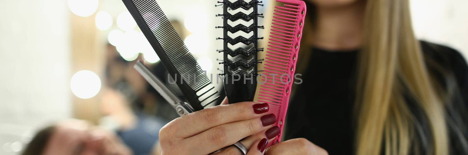 Woman hairdresser holding set of combs and scissors in a barbershop. Hairdressing tools concept