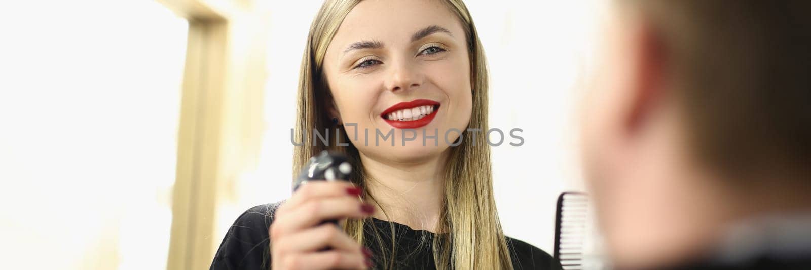 Smiling female hairdresser communicates with man in beauty salon by kuprevich