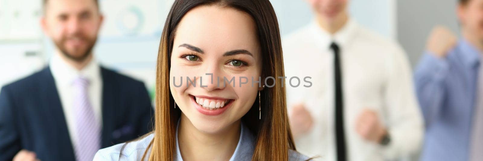 Portrait of smiling successful businesswoman and team by kuprevich