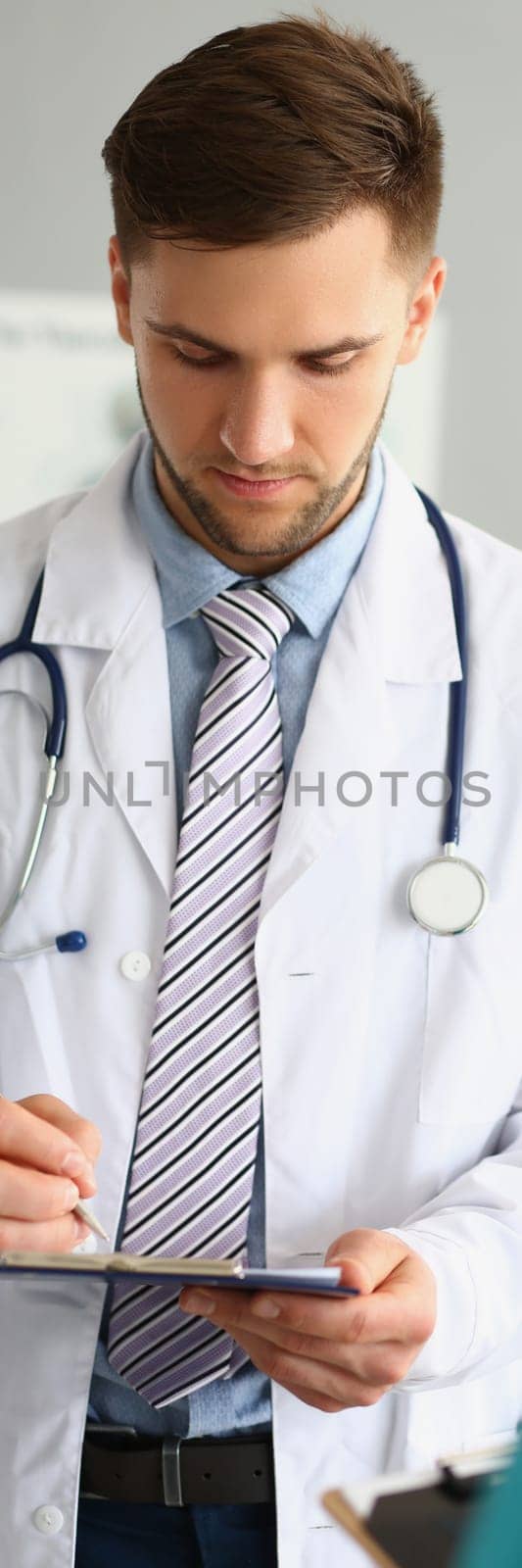 Male doctor filling out patient medical form in clinic. Medina contract and insurance concept