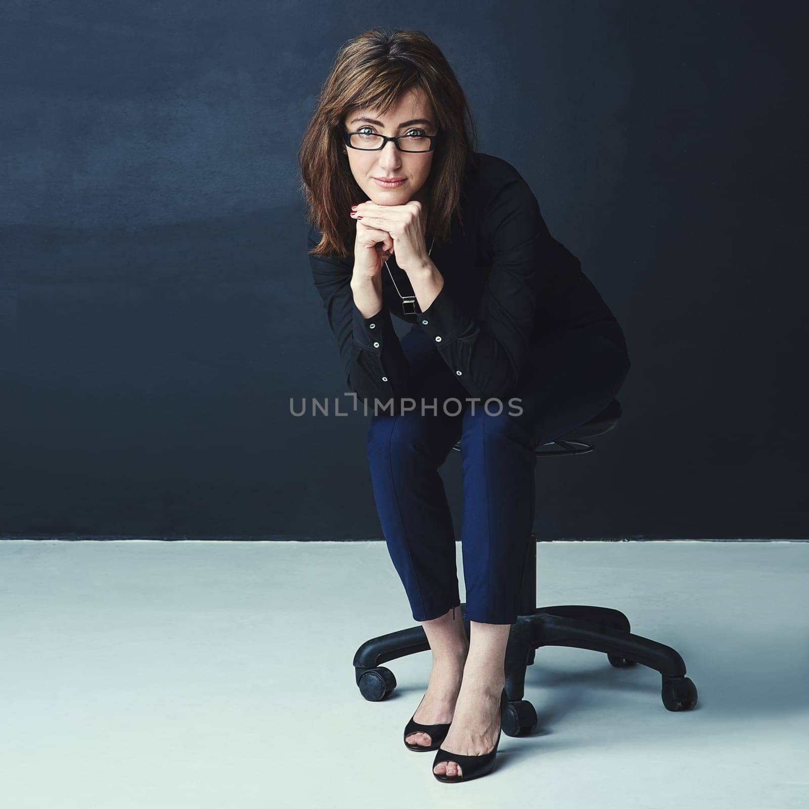 Forward-thinking is essential if you want to stay on top. Studio portrait of a corporate businesswoman posing against a dark background. by YuriArcurs