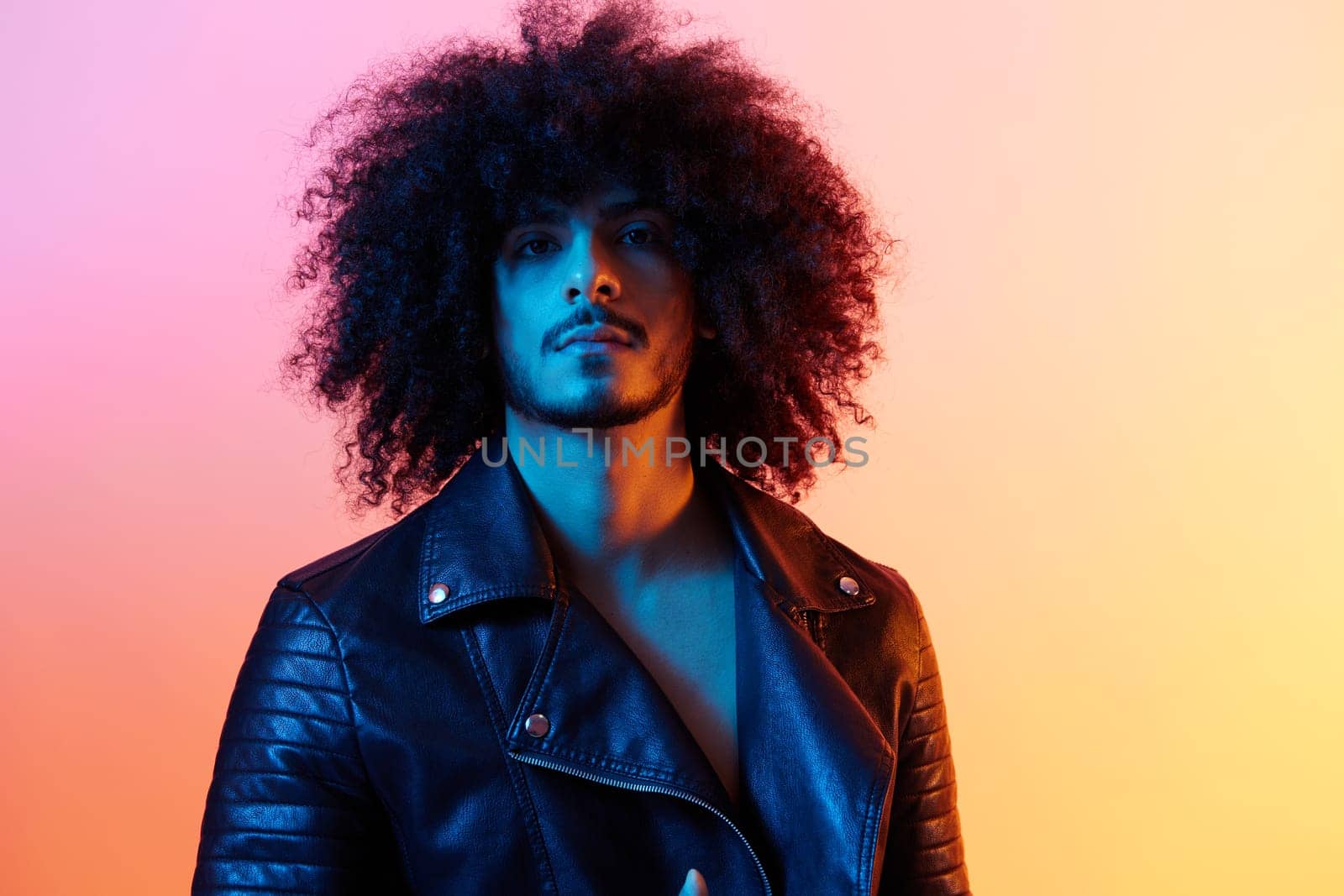 Portrait of fashion man with curly hair on red background multinational, colored light, black leather jacket trend, modern concept. by SHOTPRIME