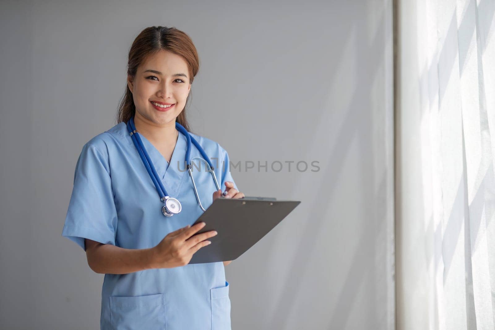 Portrait of female asian doctor standing in her office at clinic...