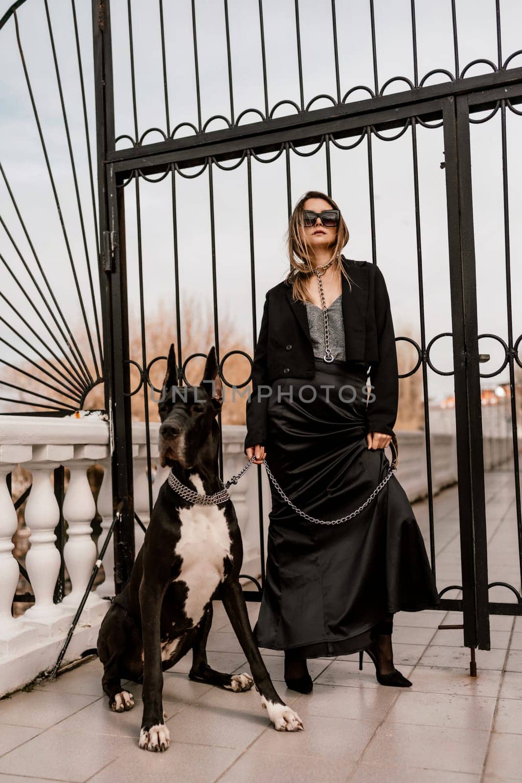 A woman walks with her Great Dane in an urban setting, enjoying the outdoors and the company of her dog