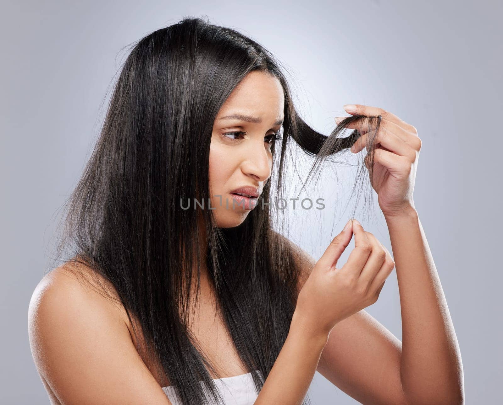 Hair problem, damage and woman in studio with worry for split ends, haircare crisis and weak tips. Beauty, salon and face of upset female person with frizz, dry texture and loss on gray background.