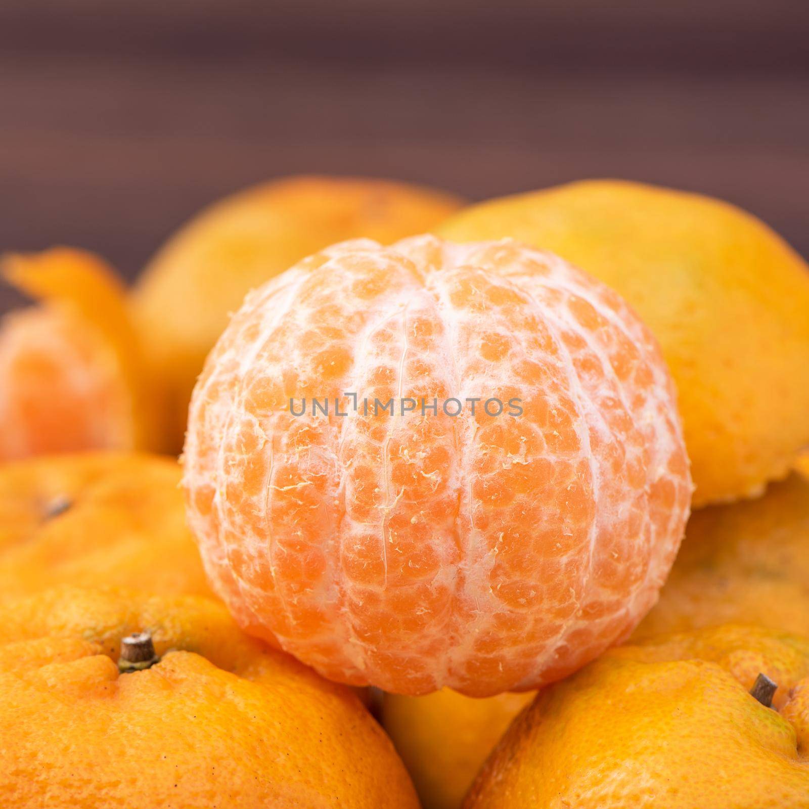 Fresh, beautiful orange color tangerine on bamboo sieve over dark wooden table. Seasonal, traditional fruit of Chinese lunar new year, close up.