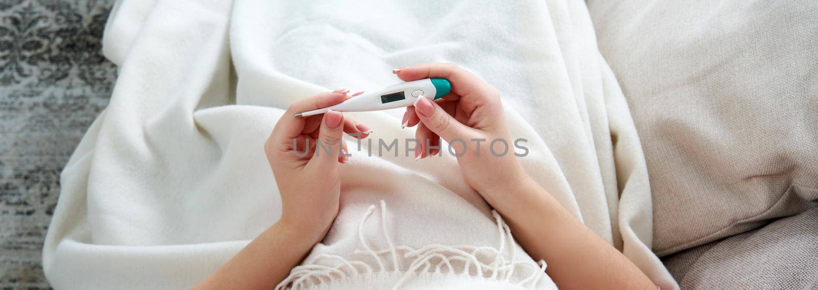 Woman looking at thermometer. Female hands holding a digital thermometer. Girl measures the temperature. Concept of fever, flue or virus