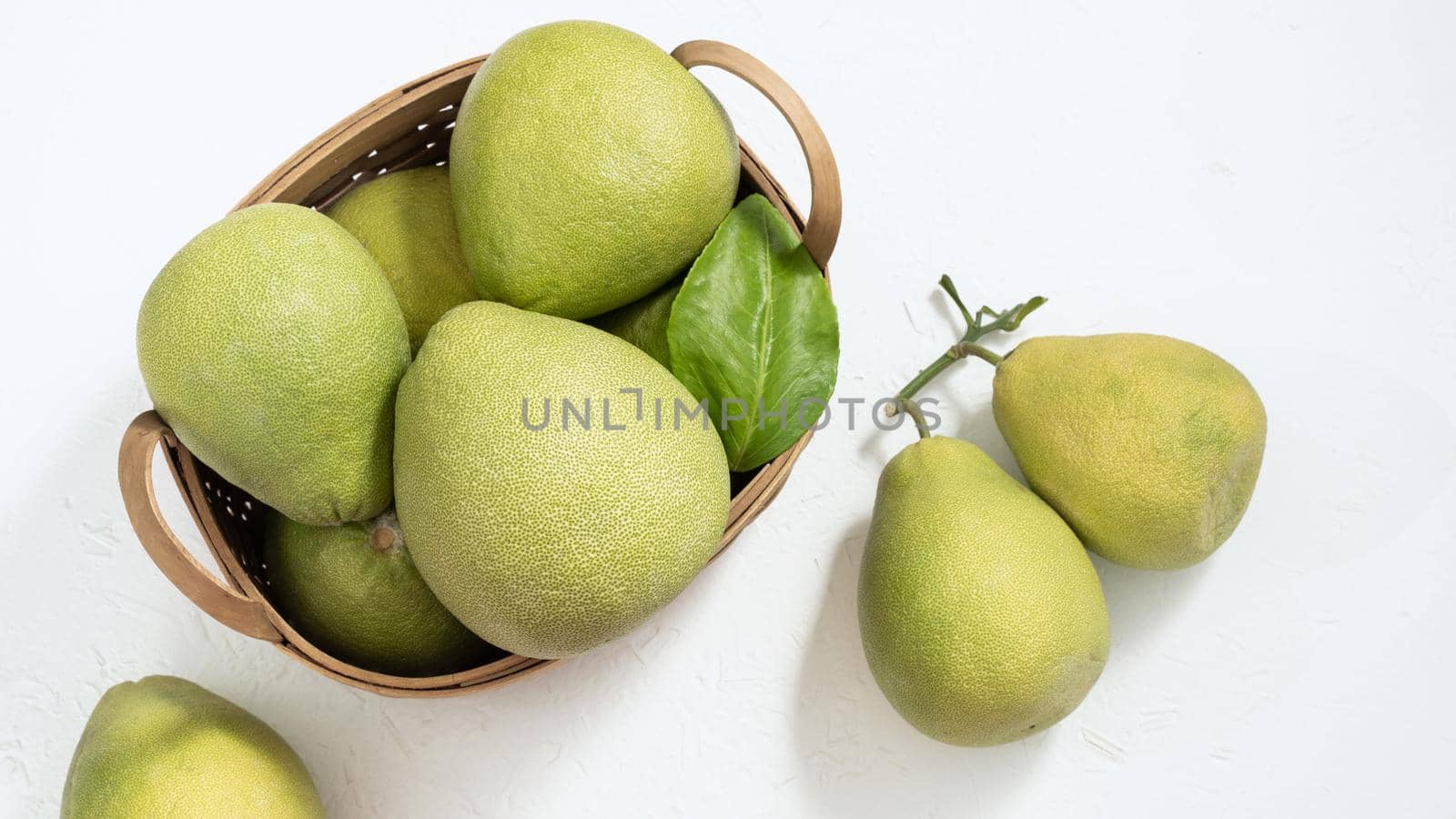 Fresh pomelo, pummelo, grapefruit, shaddock on white cement background in bamboo basket. Autumn seasonal fruit, top view, flat lay, tabletop shot.