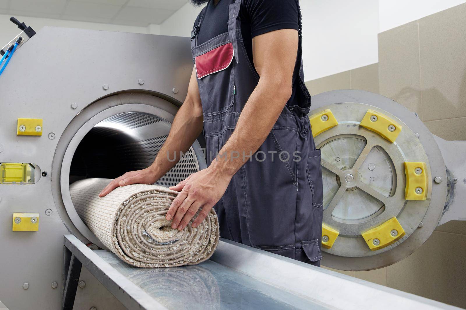 Laundry worker in the process of working on the automatic machine for drying carpets