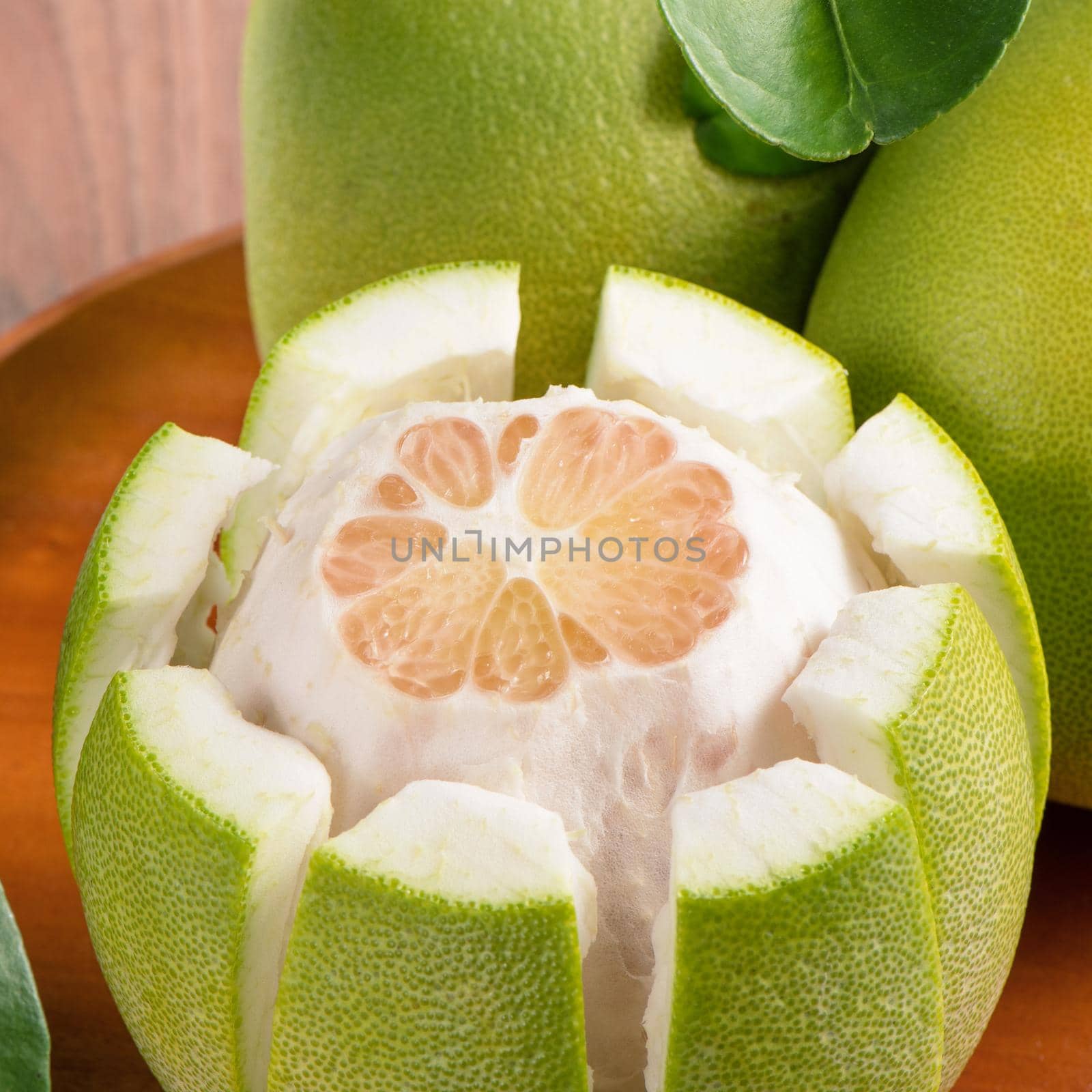 Fresh peeled pomelo, grapefruit, shaddock with green leaves on dark wooden plank table. Seasonal fruit near mid-autumn festival, close up, copy space