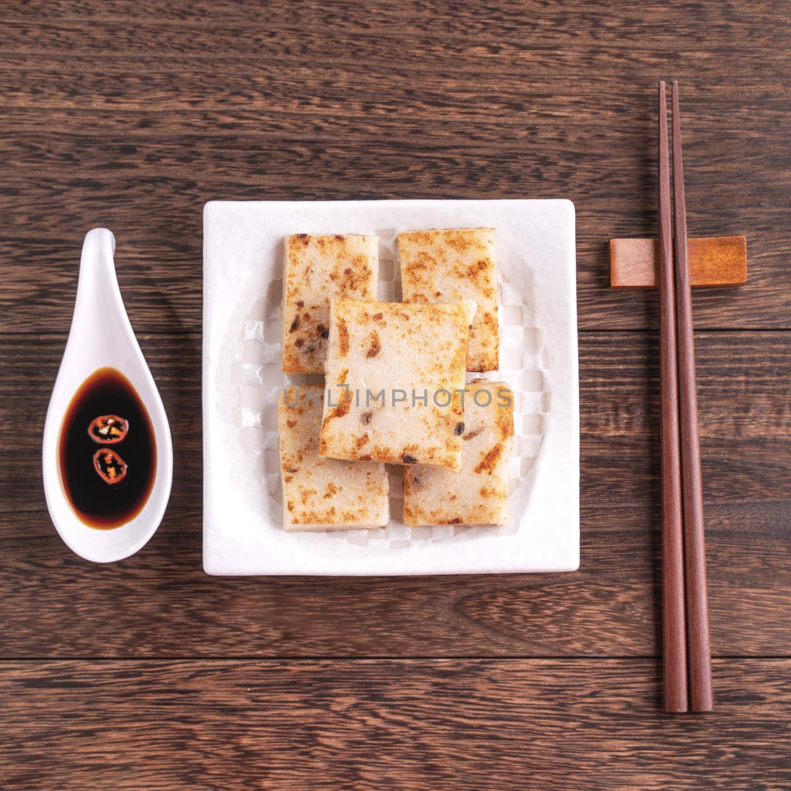 Delicious turnip cake, Chinese traditional radish cake in restaurant with soy sauce for new year's dishes, close up, copy space, top view, flat lay. by ROMIXIMAGE