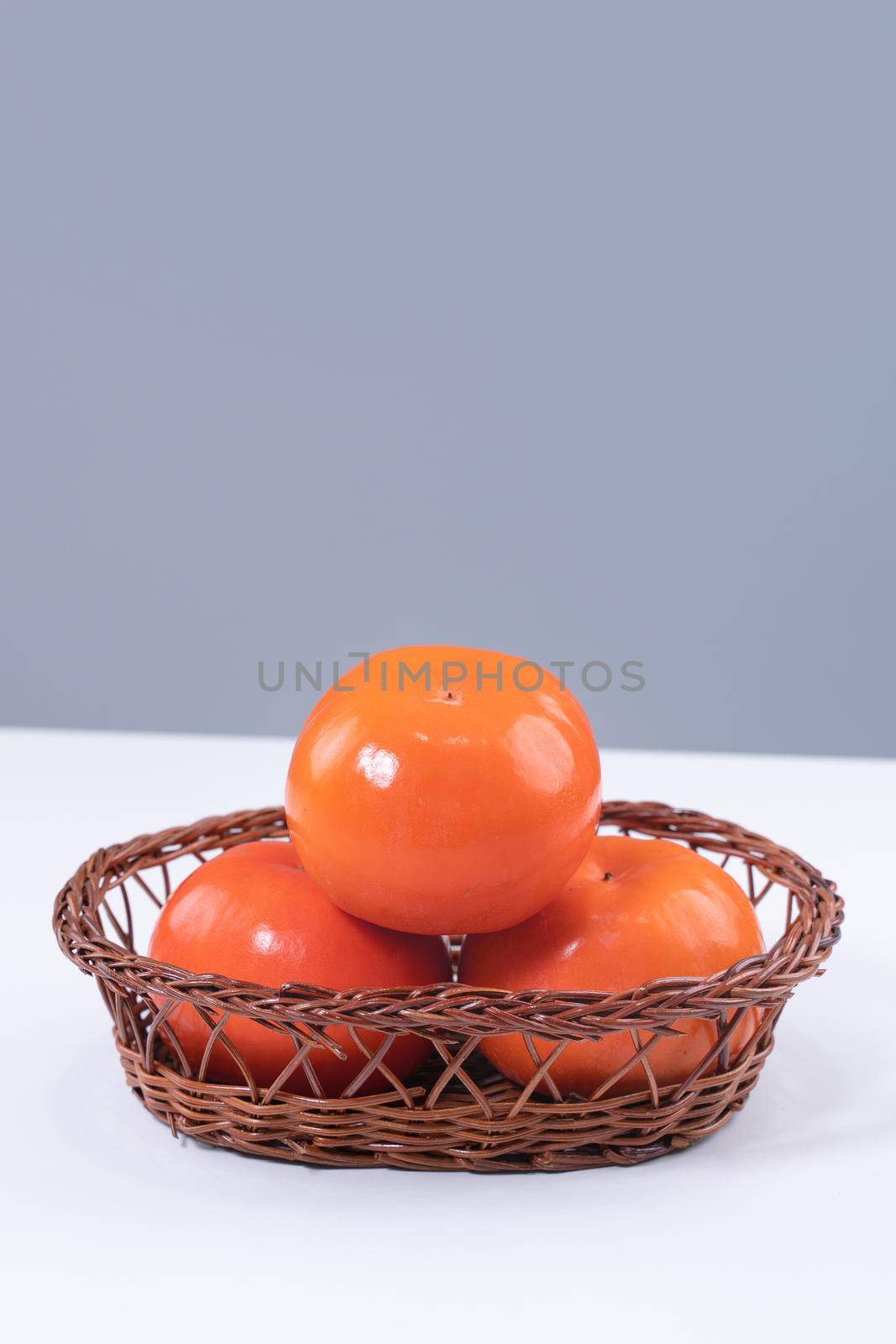 Fresh beautiful sliced sweet persimmon kaki isolated on white kitchen table with gray blue background, Chinese lunar new year design concept, close up.