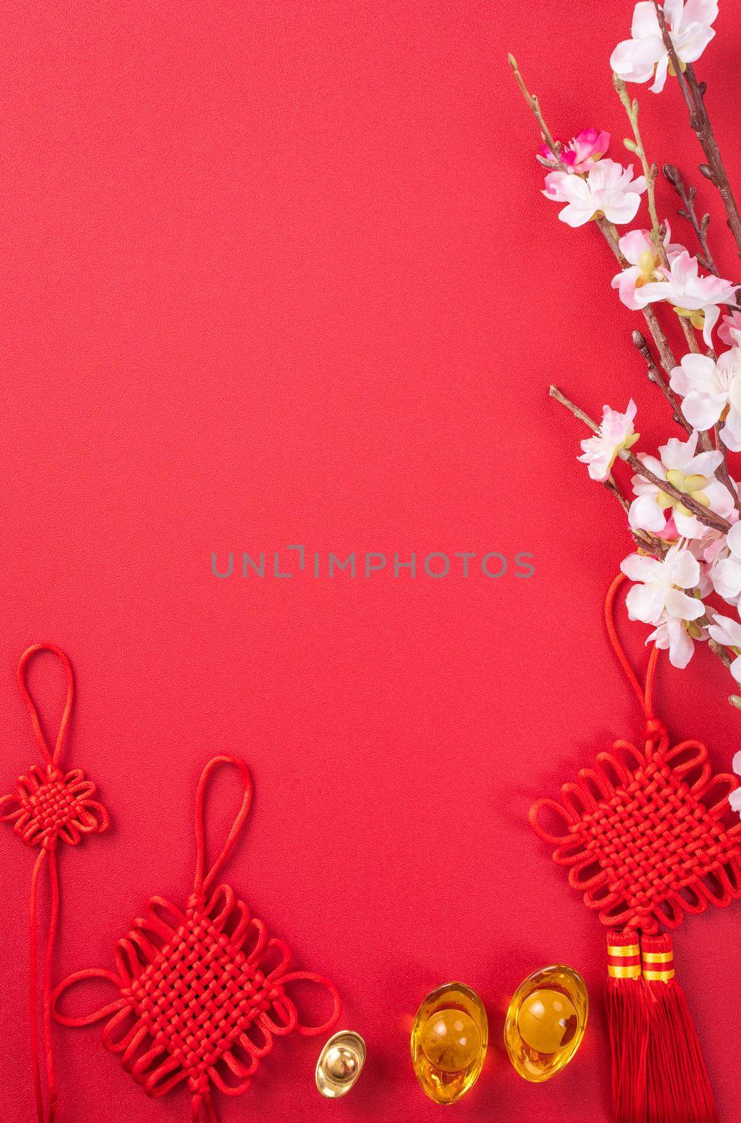 Design concept of Chinese lunar new year - Beautiful Chinese knot with plum blossom isolated on red background, flat lay, top view, overhead layout.