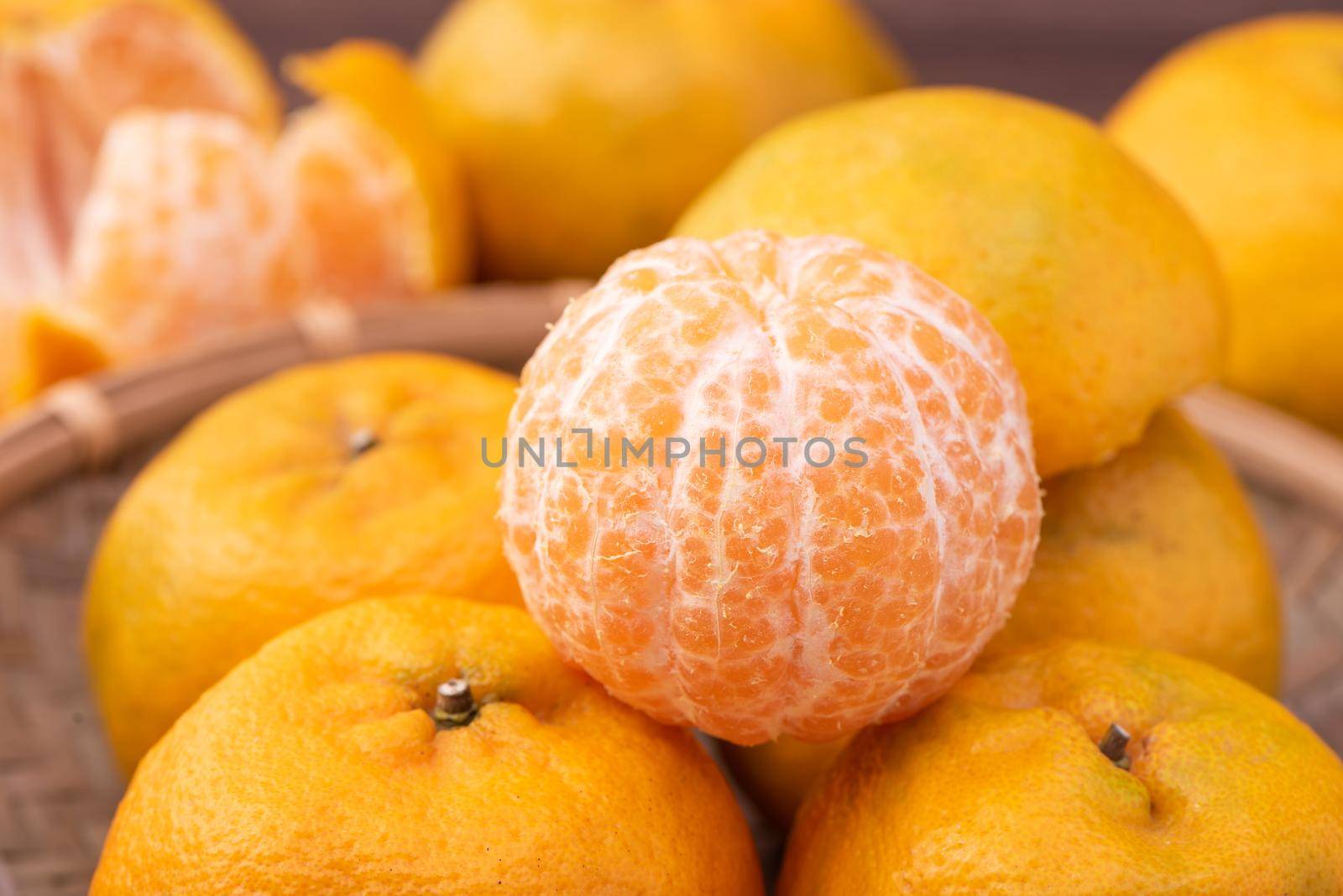 Fresh, beautiful orange color tangerine on bamboo sieve over dark wooden table. Seasonal, traditional fruit of Chinese lunar new year, close up.