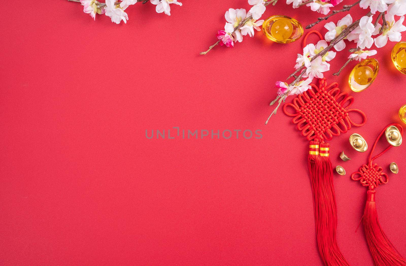 Design concept of Chinese lunar new year - Beautiful Chinese knot with plum blossom isolated on red background, flat lay, top view, overhead layout.