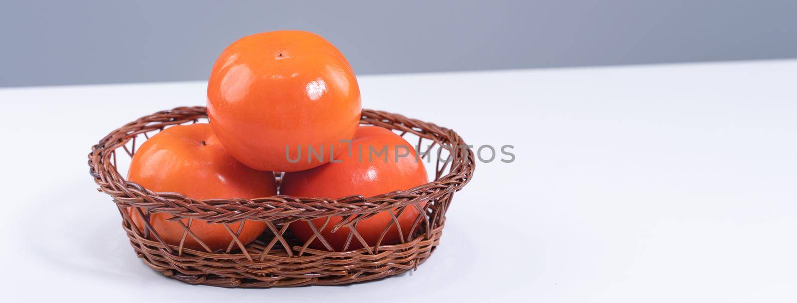 Fresh beautiful sliced sweet persimmon kaki isolated on white kitchen table with gray blue background, Chinese lunar new year design concept, close up.