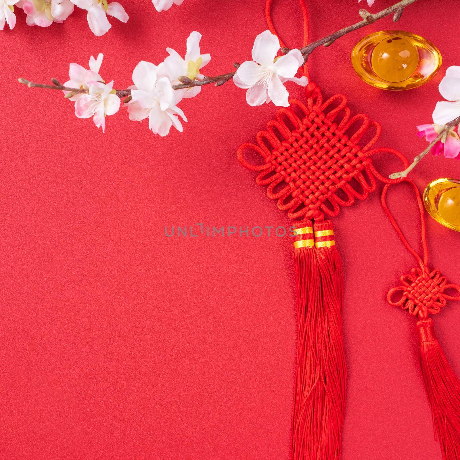 Design concept of Chinese lunar new year - Beautiful Chinese knot with plum blossom isolated on red background, flat lay, top view, overhead layout.