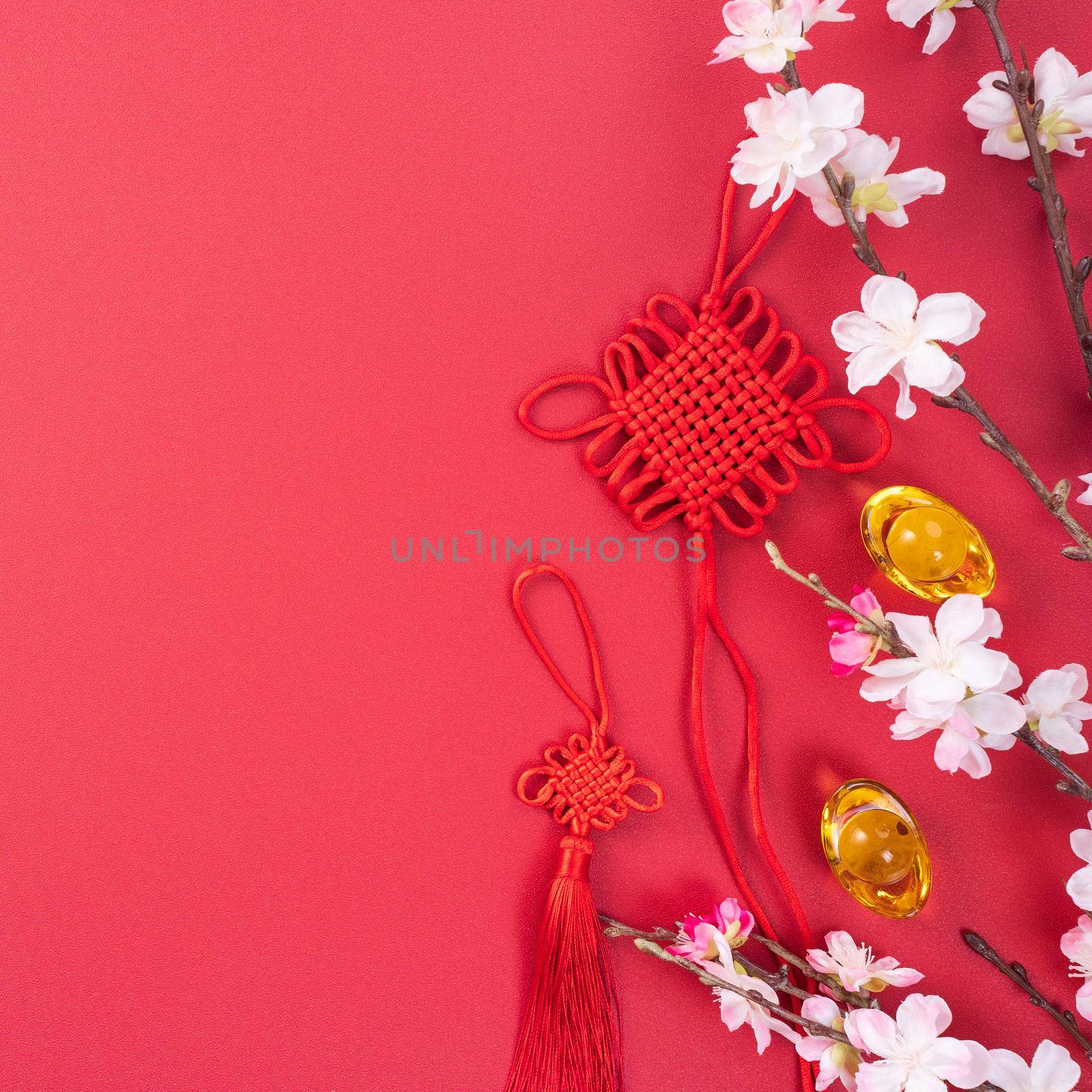 Design concept of Chinese lunar new year - Beautiful Chinese knot with plum blossom isolated on red background, flat lay, top view, overhead layout.