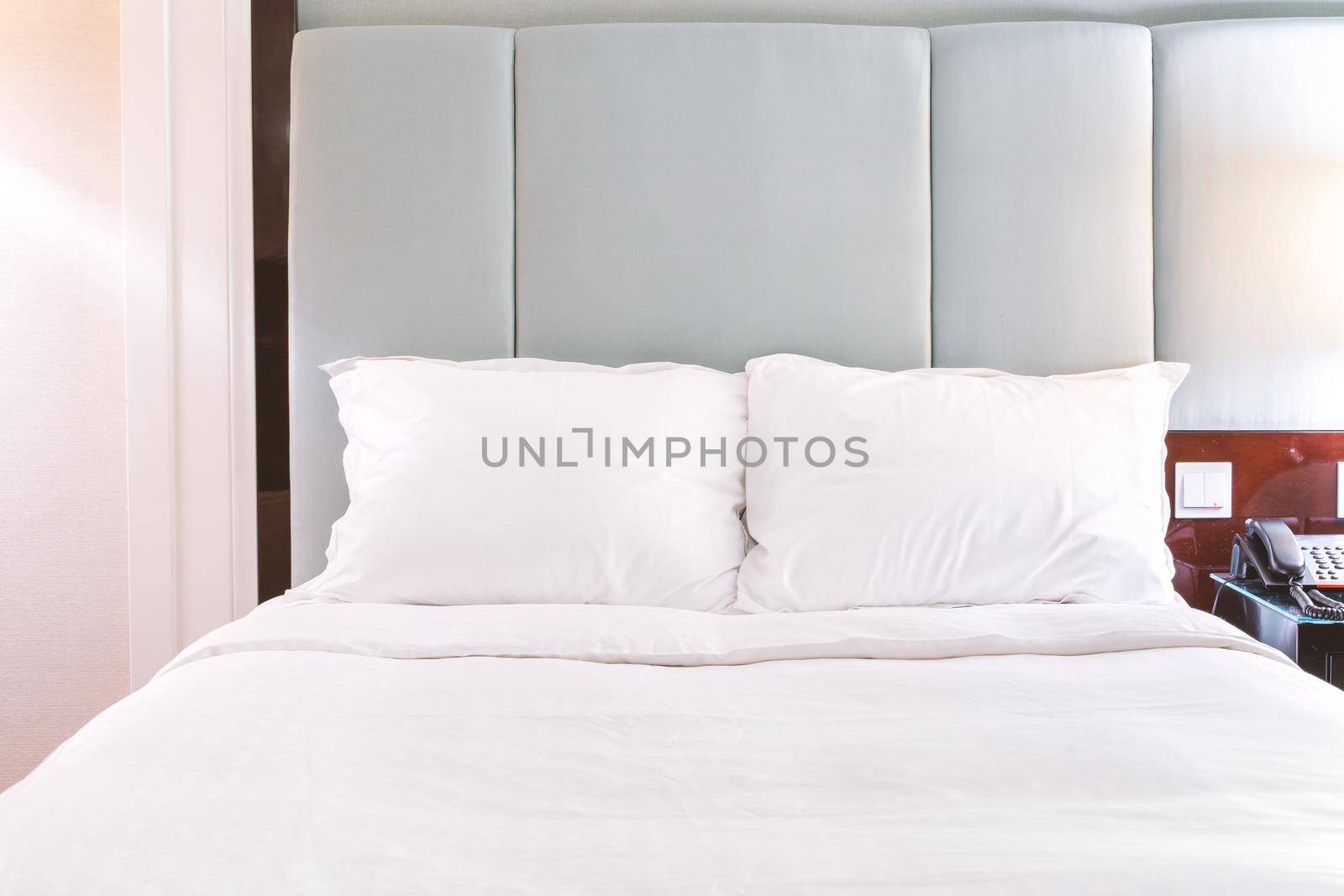 Clean and cozy modern hotel bedroom interior, warm tone room with a standing lamp, linen sofa with a cushion, design concept of luxury travel, close up. by ROMIXIMAGE