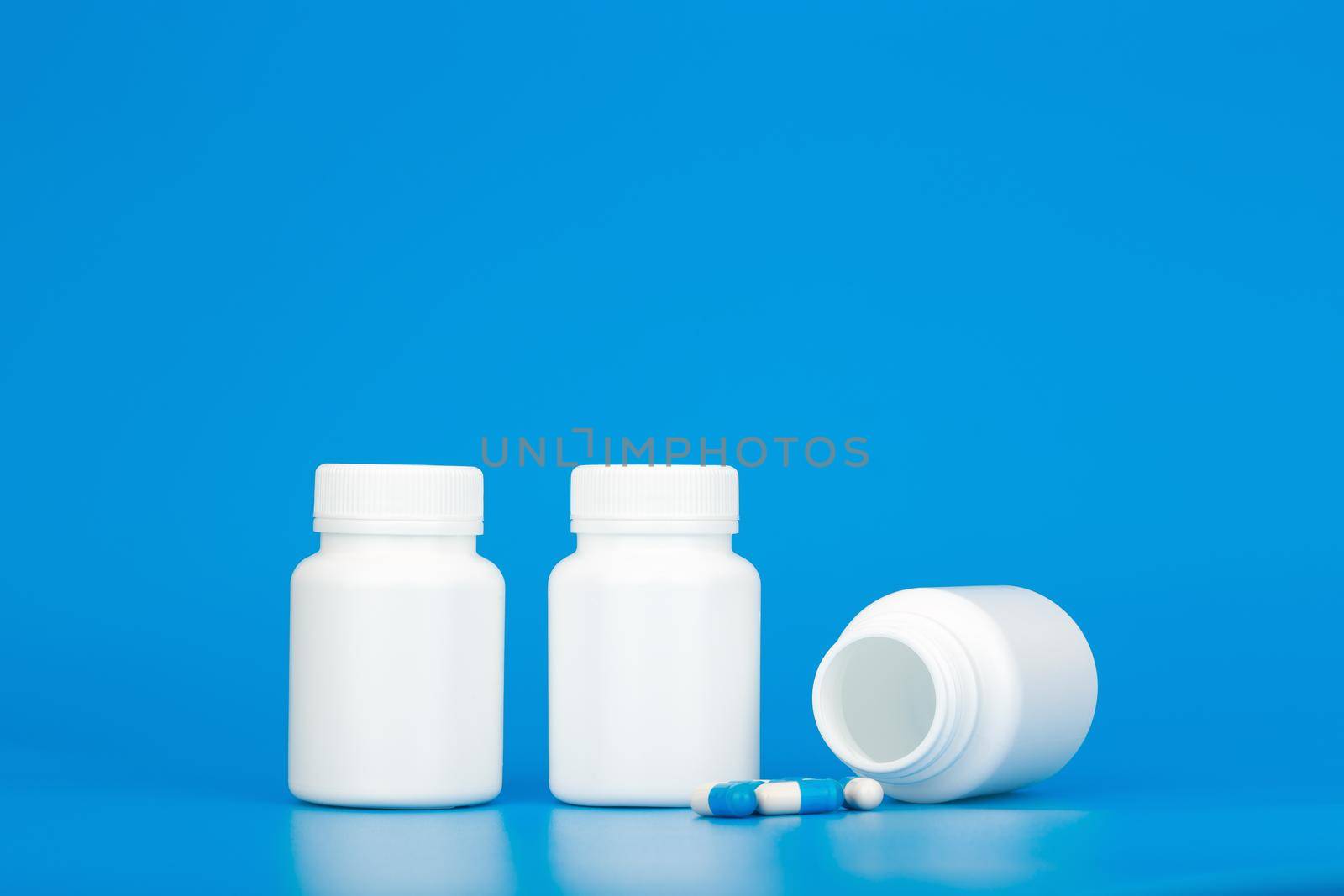 Minimal still life white medication bottles with pills against blue background with copy space. Concept of healthcare and medical treatment