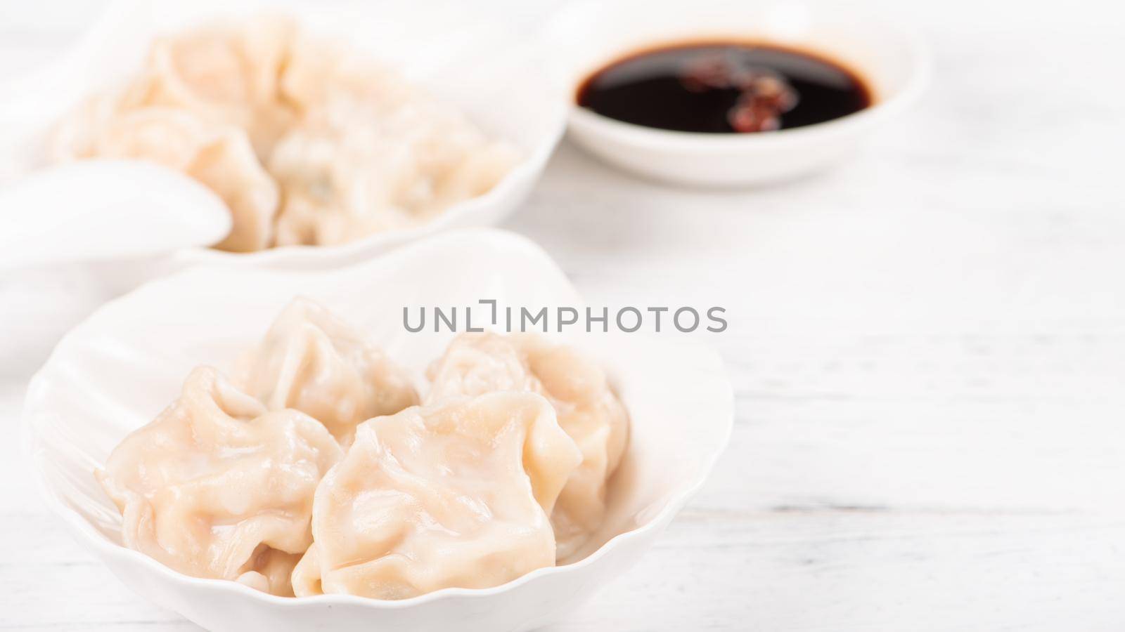 Fresh, delicious boiled pork, shrimp gyoza dumplings on white background with soy sauce and chopsticks, close up, lifestyle. Homemade design concept.