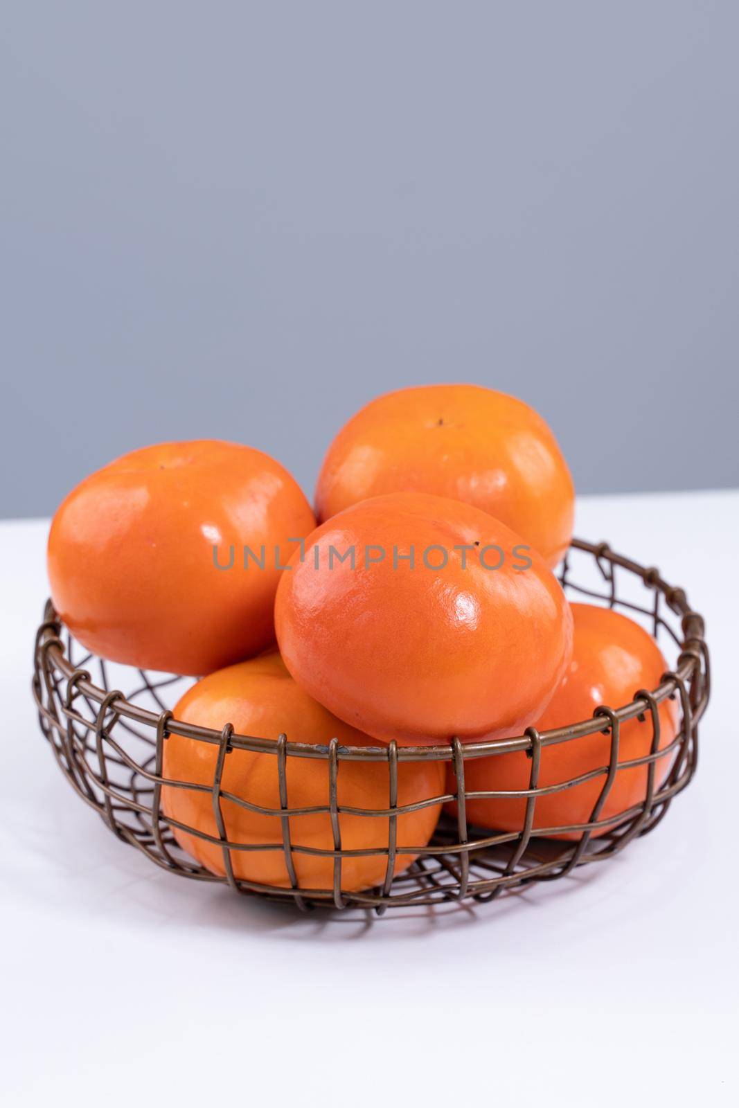 Fresh beautiful sliced sweet persimmon kaki isolated on white kitchen table with gray blue background, Chinese lunar new year design concept, close up.