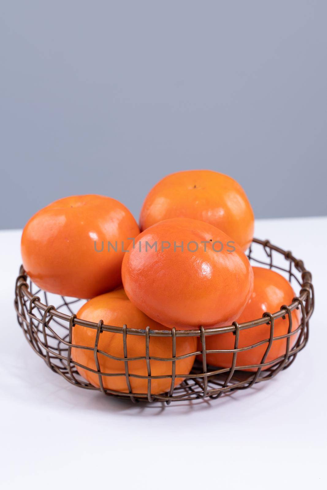 Fresh beautiful sliced sweet persimmon kaki isolated on white kitchen table with gray blue background, Chinese lunar new year design concept, close up. by ROMIXIMAGE