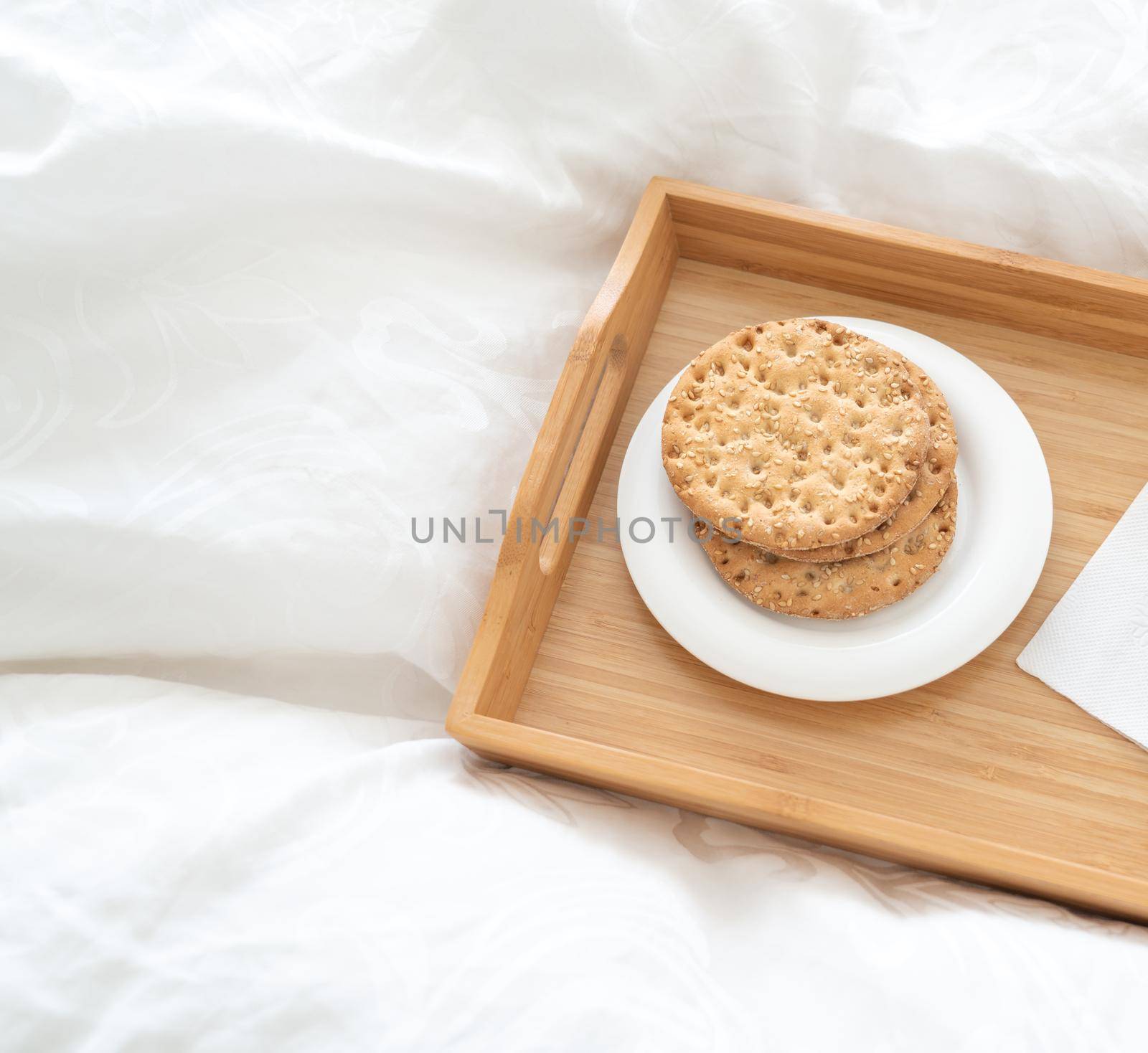 Tray with water and crackers breakfast on a bed