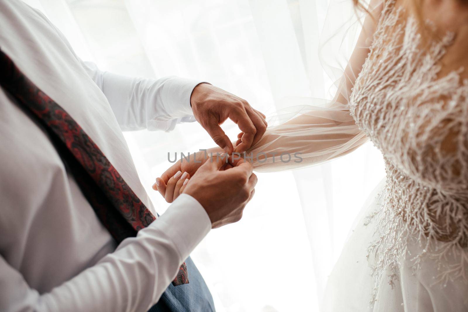 Groom is helping a bride with her dress, a romantic concept