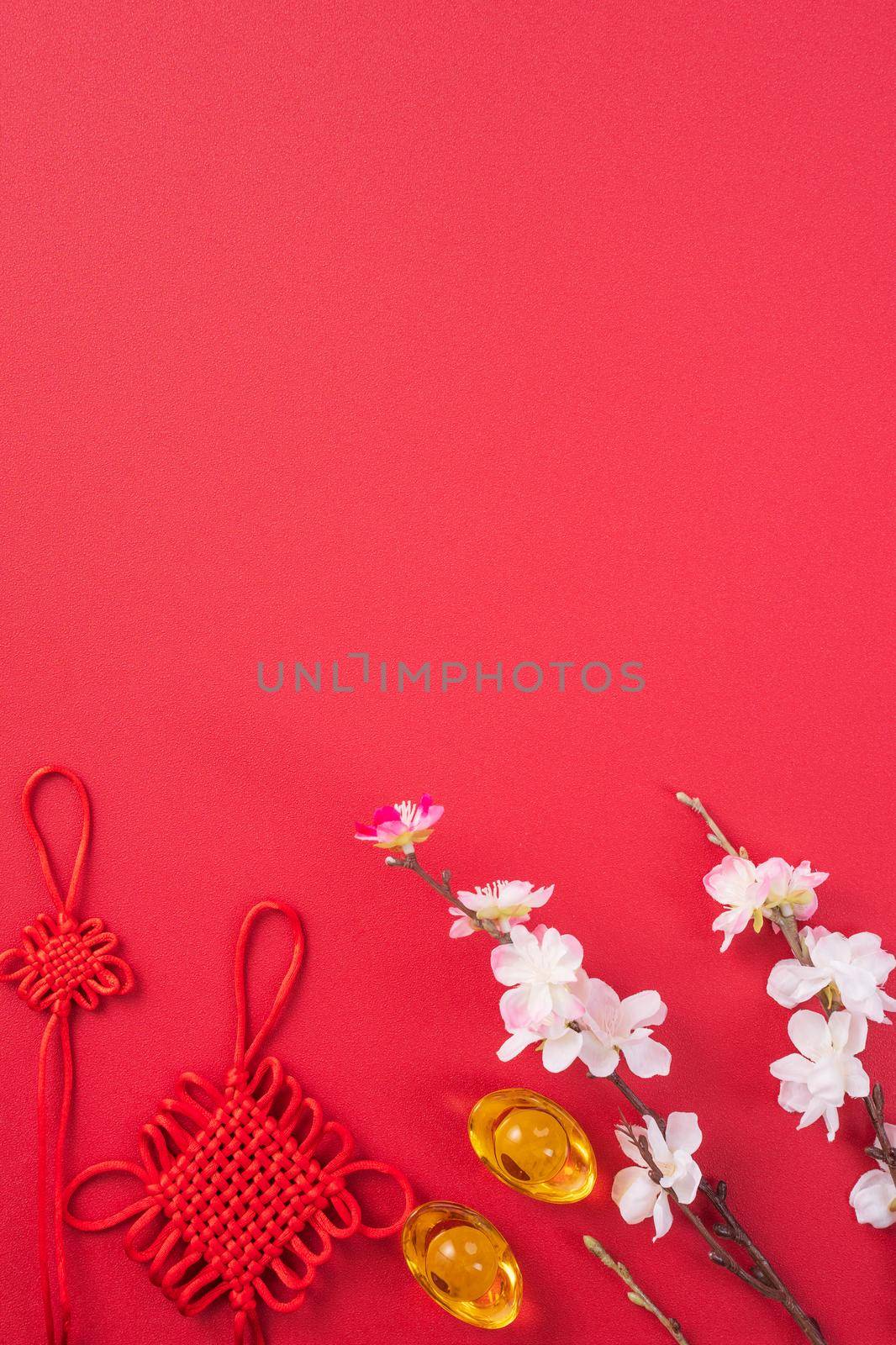 Design concept of Chinese lunar new year - Beautiful Chinese knot with plum blossom isolated on red background, flat lay, top view, overhead layout.