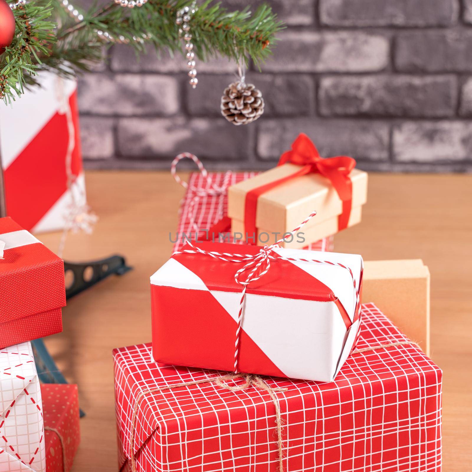 Decorated Christmas tree with wrapped beautiful red and white gifts at home with black brick wall, festive design concept, close up.