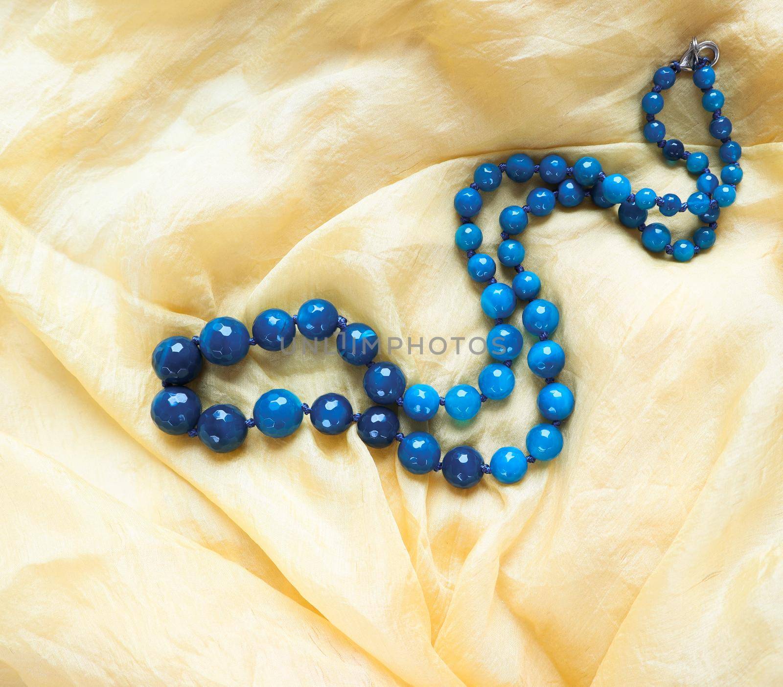 Beautiful necklace of dark blue faceted agate on yellow shiny silk.