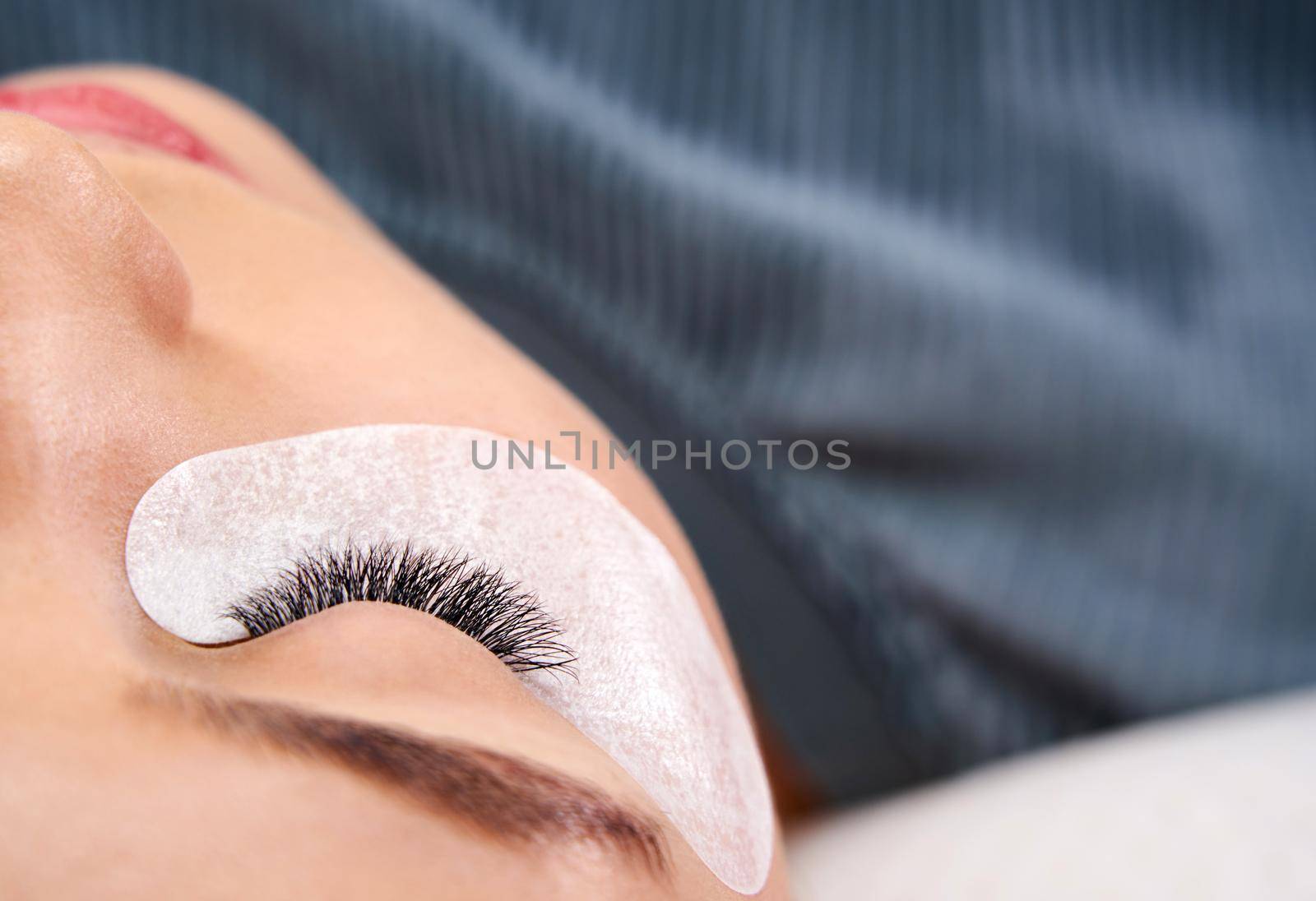 Beautiful Woman with long lashes in a beauty salon. Eyelash extension procedure by Mariakray