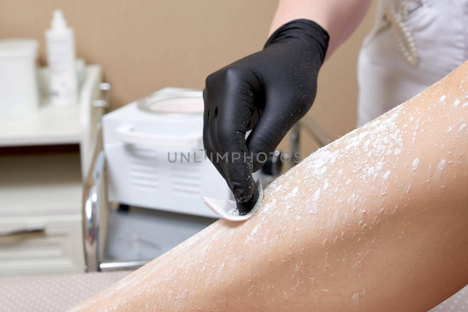 Beautician getting ready to wax female legs in spa center
