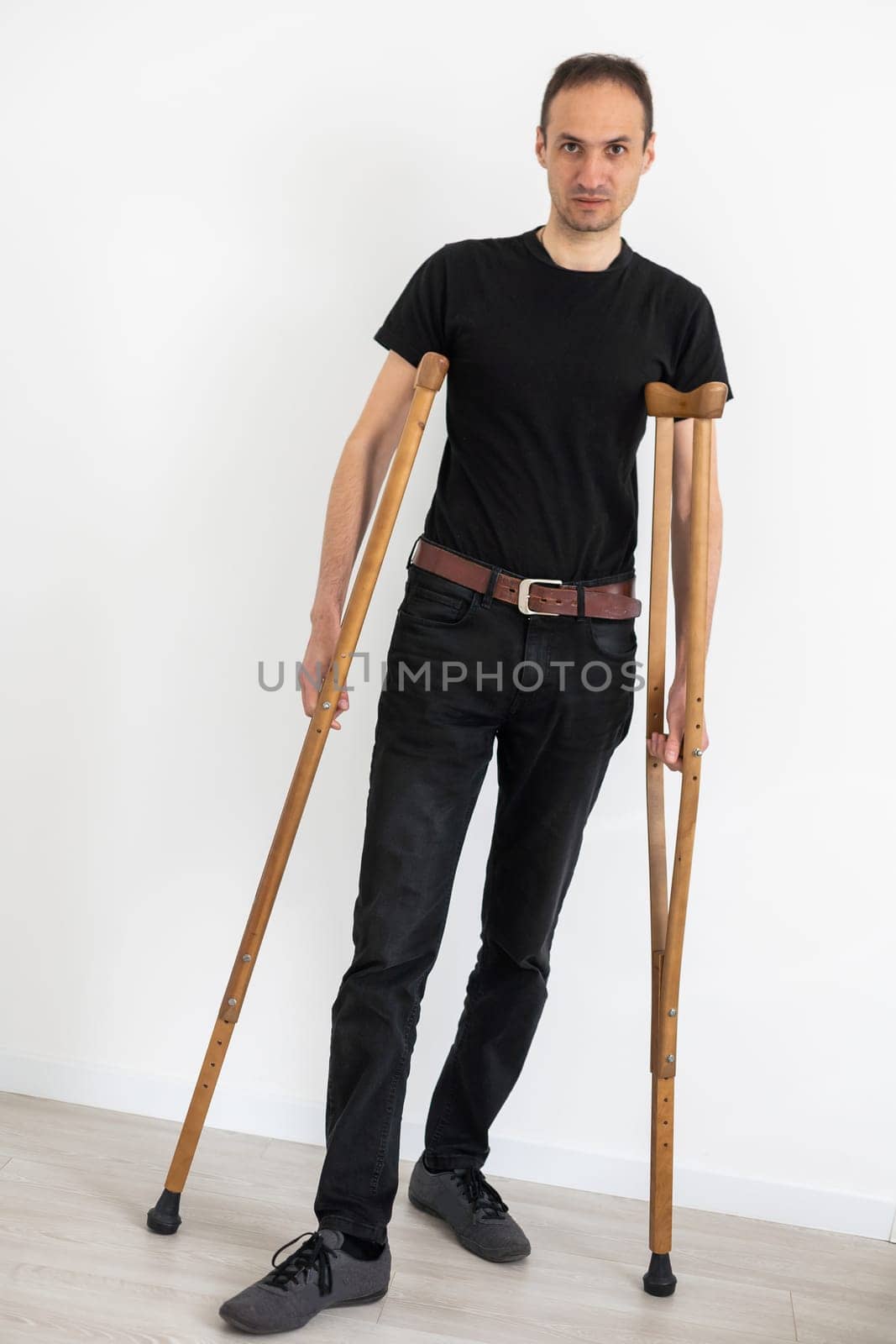 Young hispanic man confident walking using crutches at room by Andelov13