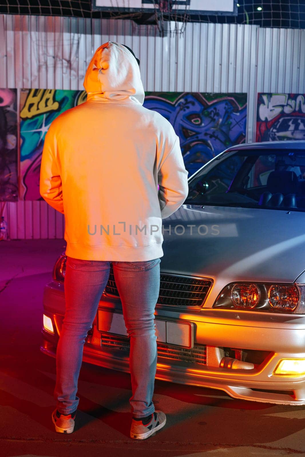 A young man standing next to his sport car at night parking by Fabrikasimf