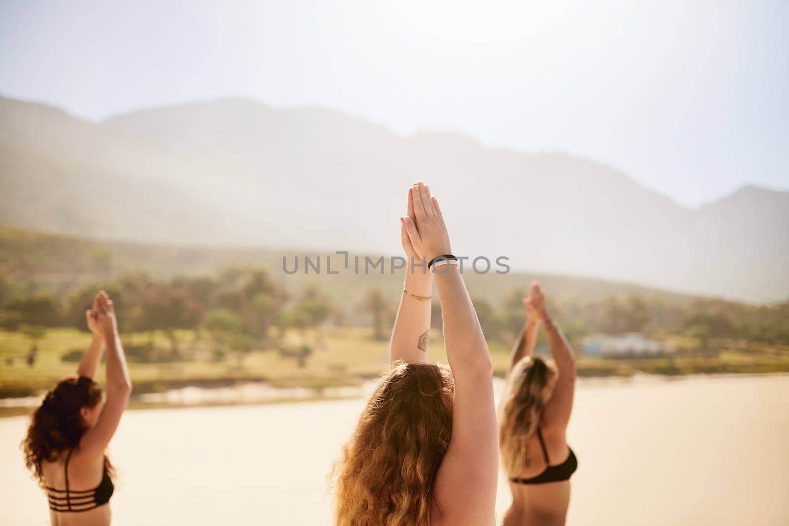 Yoga has the power to bring you closer to lasting happiness. three young women practising yoga on the beach. by YuriArcurs