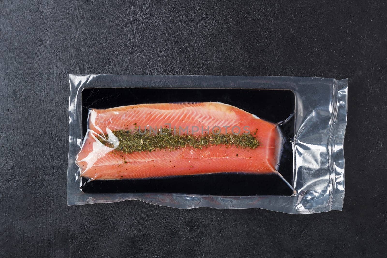 Fish fillet in vacuum packaging, on a black background. Red fish, trout.