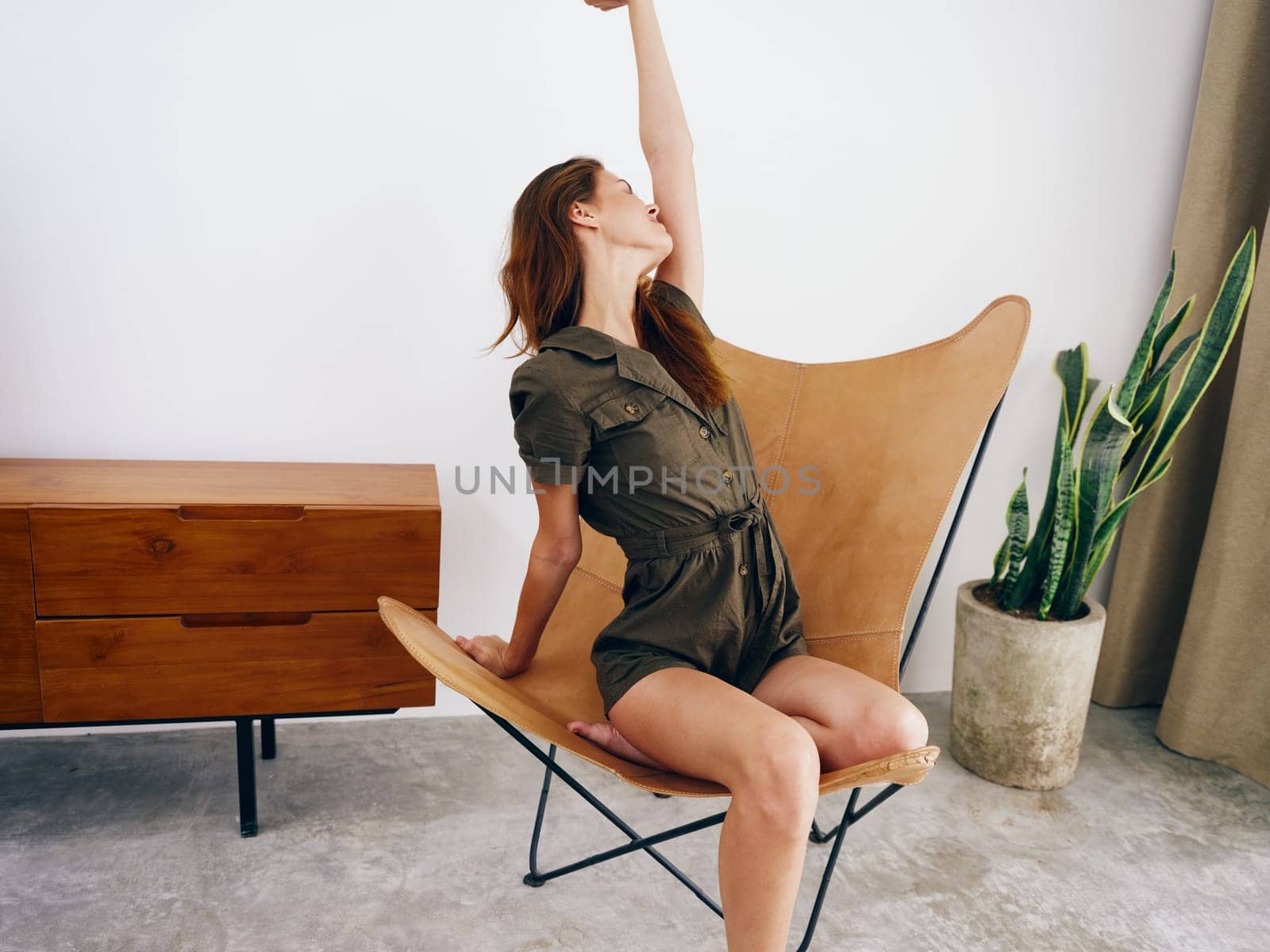 Woman model sits on a chair at home smile, fun and relaxation, modern stylish interior scandia lifestyle, copy space. by SHOTPRIME