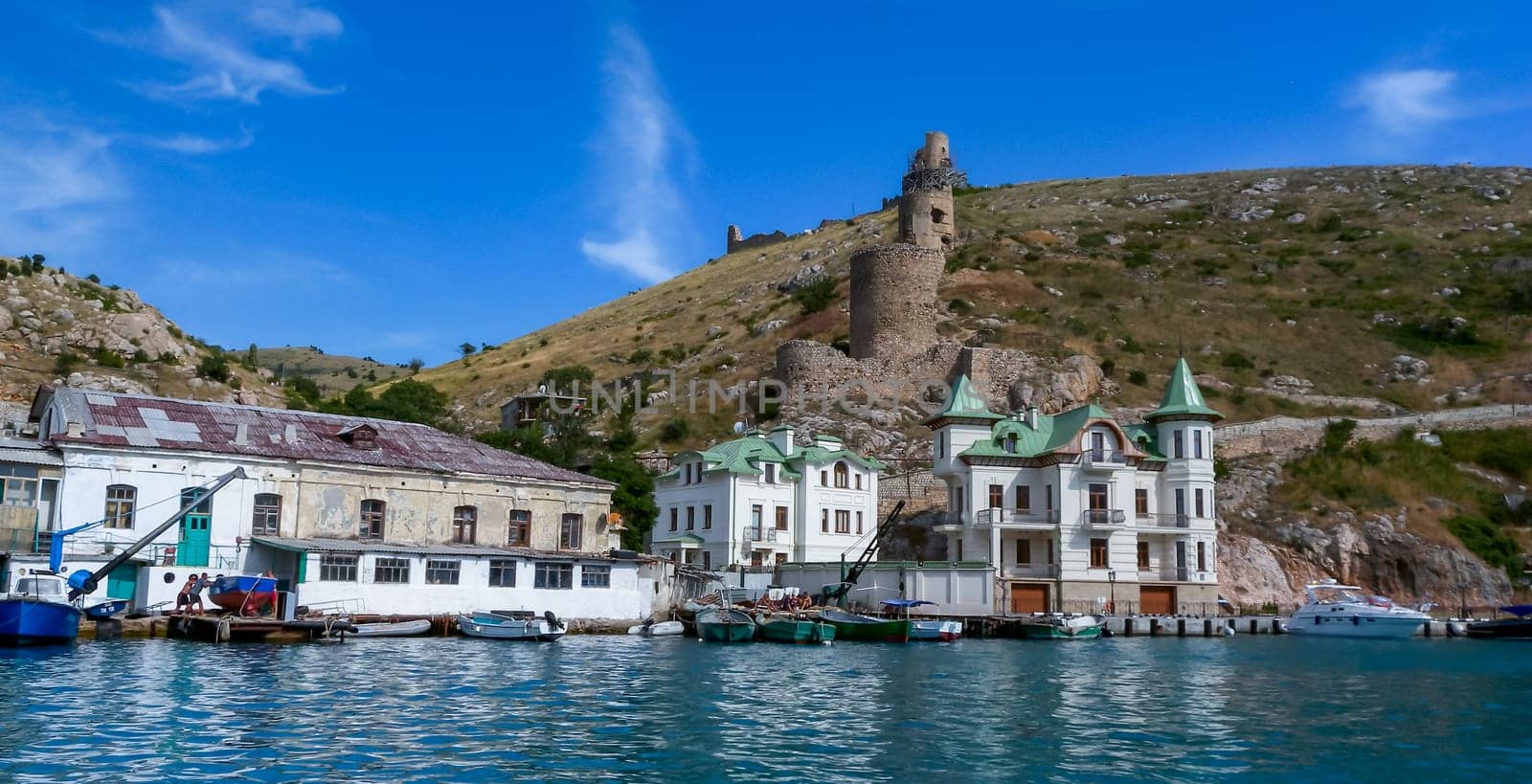 BALAKLAVA, UKRAINE - JUNE 27, 2012: View from the sea to the ruins of the fortress and modern buildings on the shore in Balaklava Bay, Black Sea