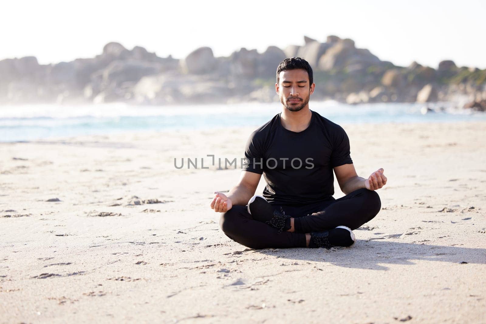 Freedom, man sitting on the beach and meditation for peace of mind during summer. Relax or harmony meditating, mental health and male person on the sea sand for health wellness in fresh air outdoors.