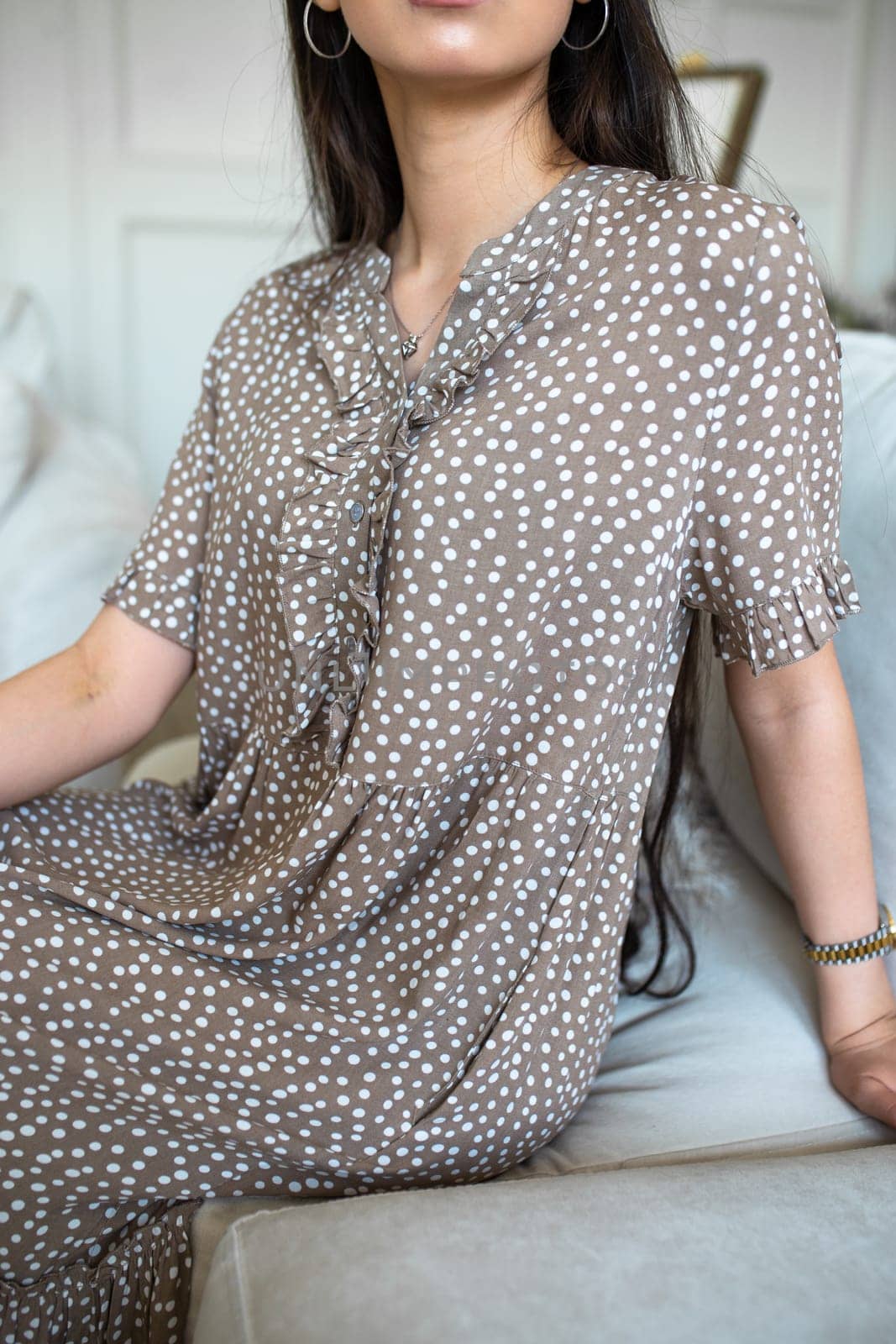 a girl without a face in a coffee-colored dress with white dots.