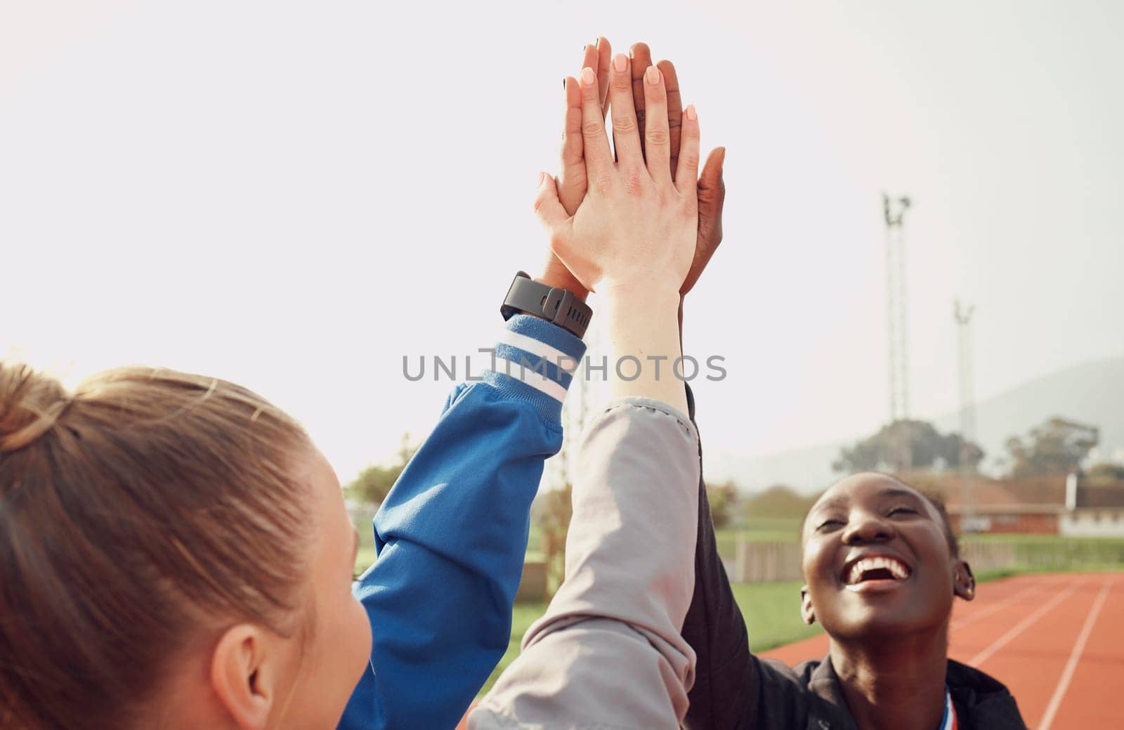 People, diversity and high five in fitness for teamwork, unity or trust together on stadium track. Happy athlete group touching hands in team building for sports motivation, support or goals outdoors.