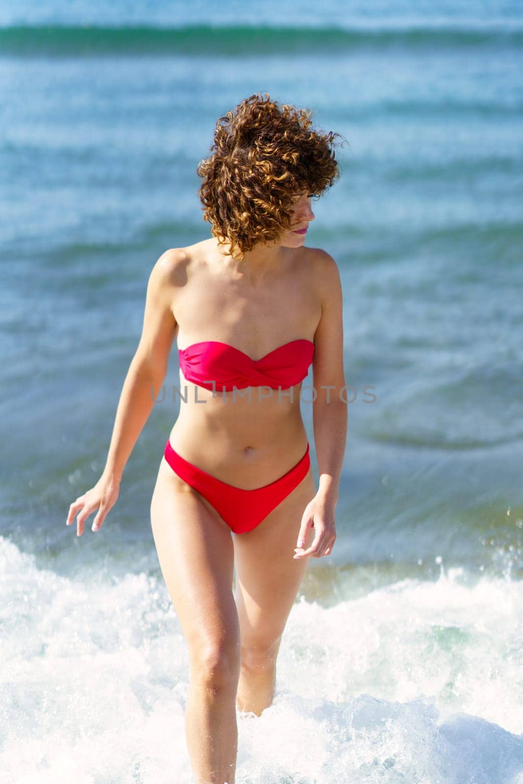Female in swimwear walking in ocean water at beach by javiindy