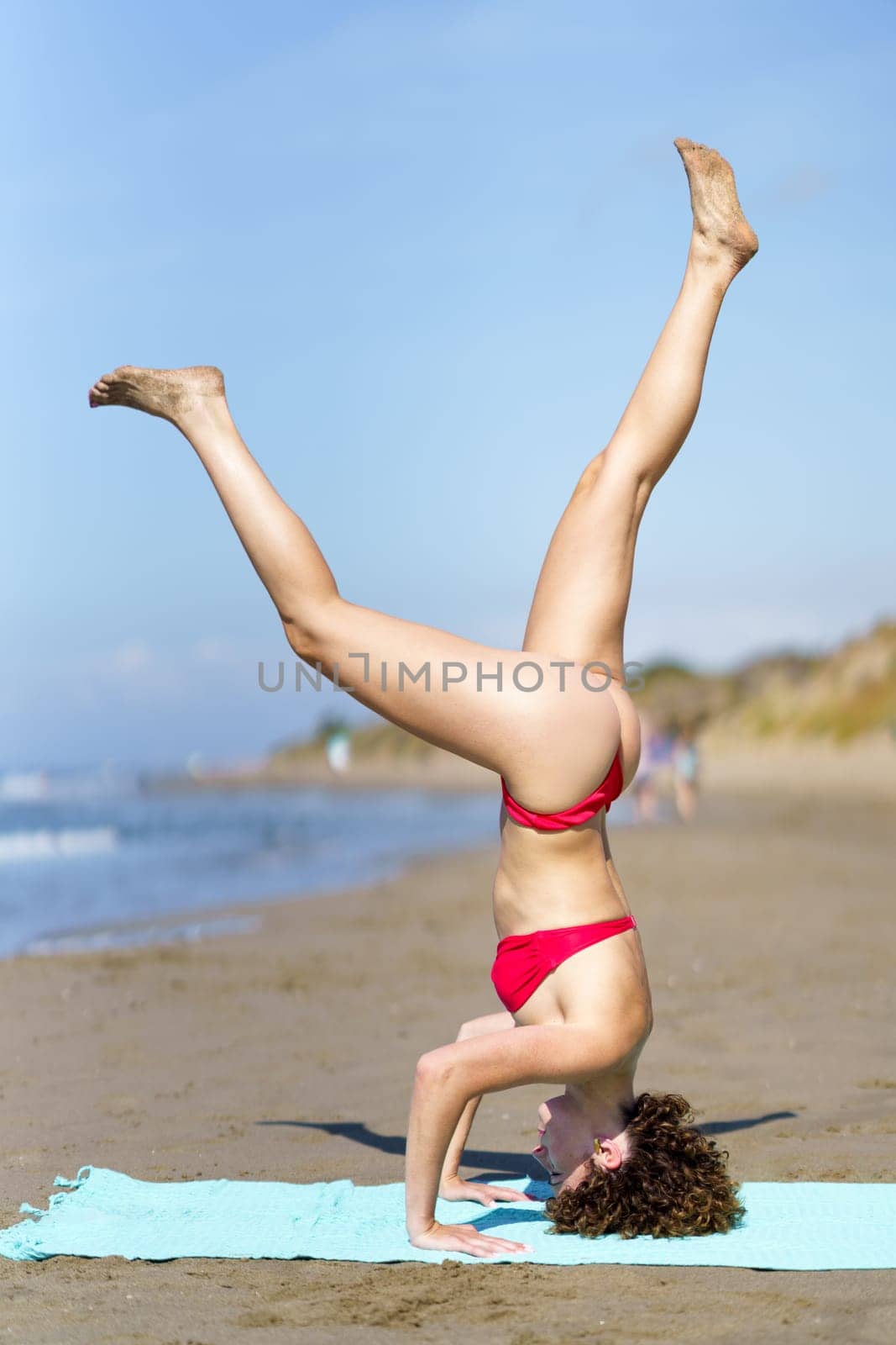 Slim woman practicing yoga on sandy beach by javiindy