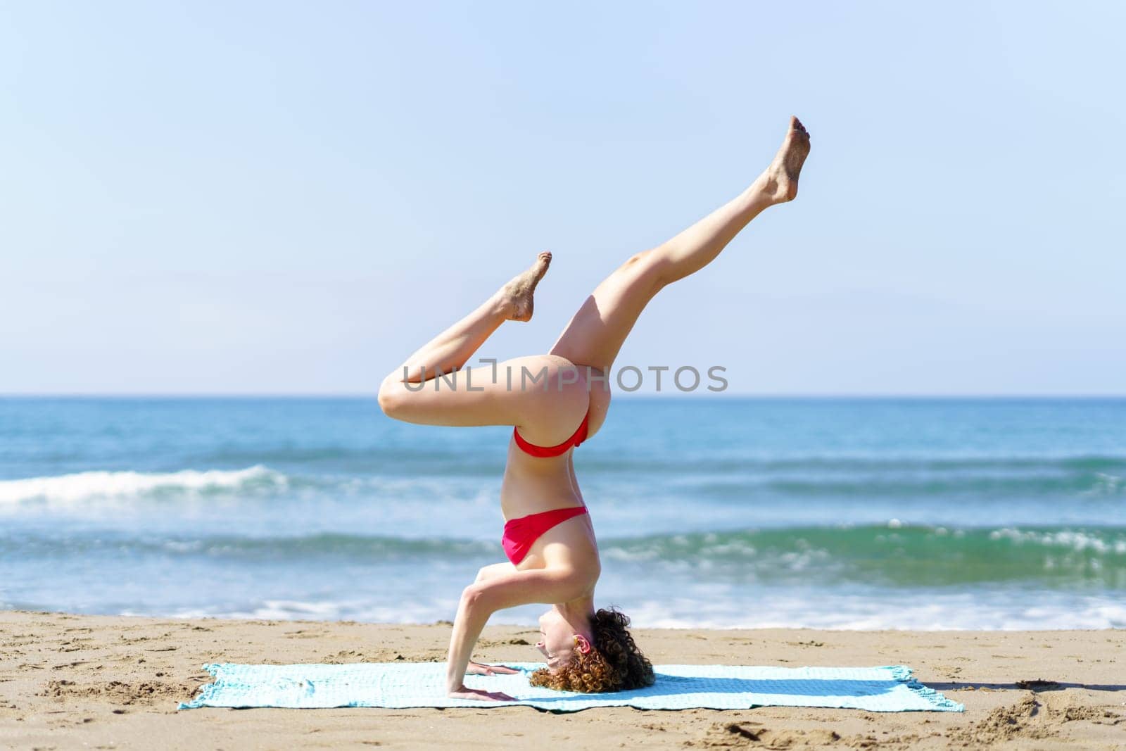 Flexible woman in bikini doing yoga in beach by javiindy